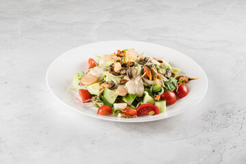 Salad with mussel, shrimp, tomato cherry, cucumber, zucchini pasta, microgreen, yogurt sauce on white plate on light table.