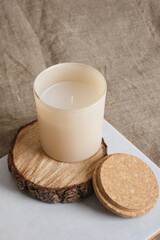 beige aroma candle on a wooden podium from a saw cut from a tree. natural candles for aroma therapy