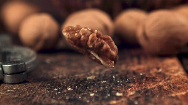 The super slow motion of the walnut grain falls on the table. On a wooden background. Filmed on a high-speed camera at 1000 fps.