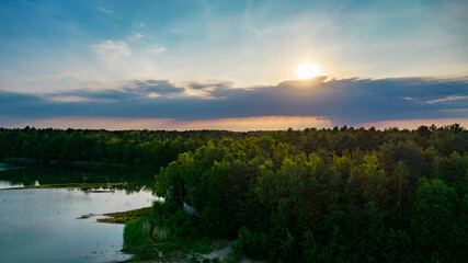 Aerial view of a beautiful and dramatic sunset over a forest lake reflected in the water, landscape drone shot. Blakheide, Beerse, Belgium. High quality photo