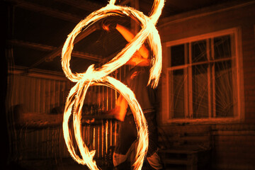 Spinning fire dancer performing burning fire poi dance