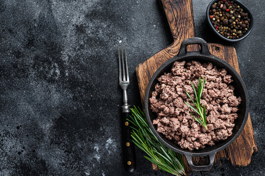Fried mince beef meat in a pan for cooking pasta. Black background. Top view. Copy space