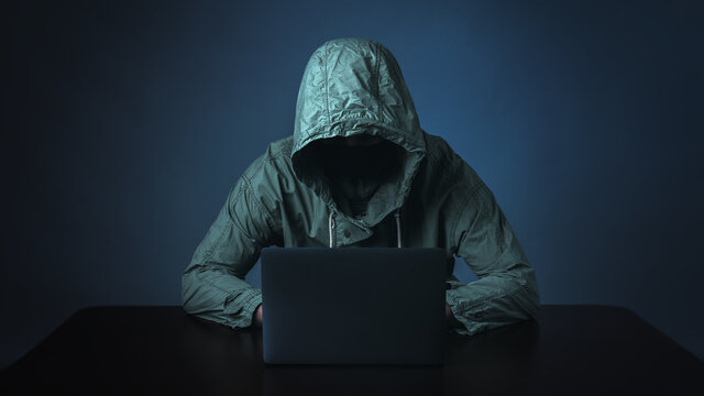 Hacker.Hacker working on laptop in the dark.