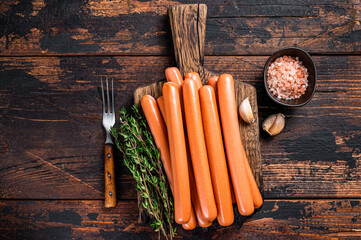 Frankfurter sausages on wooden cutting board. Dark Wooden background. Top view - obrazy, fototapety, plakaty