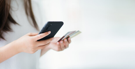 Focus on hand. young asian woman using smart phone shopping or paying online and blur another hand holding credit card