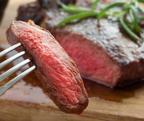 medium roast rib-eye steak on wooden plate with pepper and salt