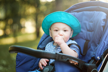 baby sucking thumb in carriage in the park