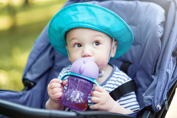 baby drinks from bottle and sitting in a baby carriage