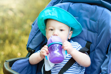 baby drinks from bottle and sitting in a baby carriage