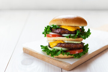 Vegan cheeseburger on a wooden board. Horizontal orientation, copy space.