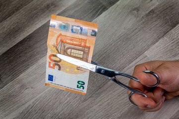 man cutting 50 euro banknotes with scissors