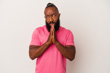 Obraz premium African american man with beard isolated on pink background praying, showing devotion, religious person looking for divine inspiration.
