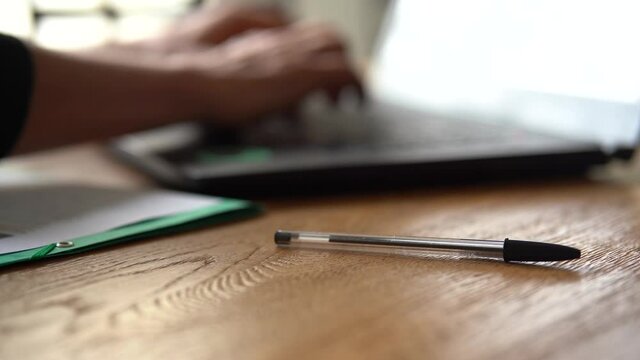 Un homme travaille sur son ordi, prend son crayon et notes des choses.