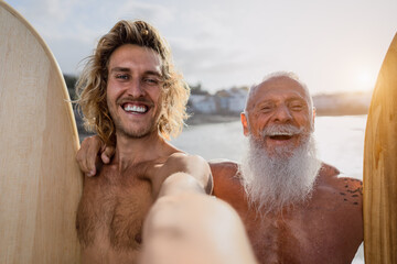 Happy fit surfers taking selfie while having fun surfing together at sunset time - Extreme sport...