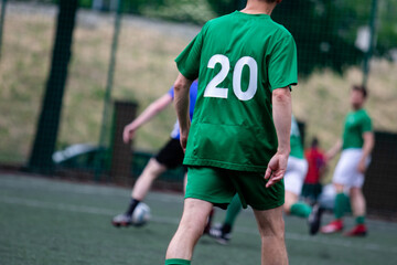 Young man in green t-shirt with number twenty during soccer match on soccer field