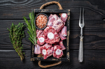 Raw veal beef Oxtail Meat in wooden tray with thyme. Black wooden background. Top view - obrazy, fototapety, plakaty