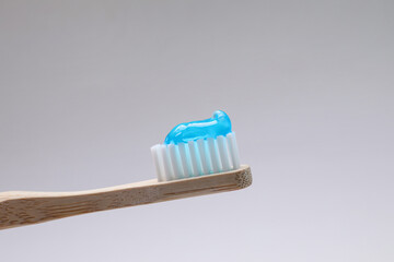 Wooden brush with toothpaste on grey background, closeup