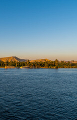 Vertical sunset view of boats and vegetation on the Nile River near Luxor, Egypt