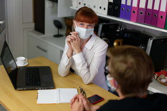 High resolution photo of adult caucasian woman manager in mask communicates with visitor in office