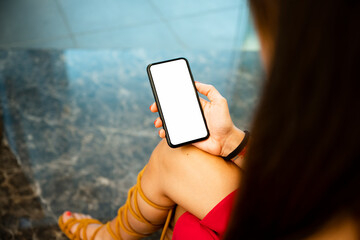 (Selective focus) Defocused young girl holding a smartphone with a white screen in an airport lounge. Copy space, concept of showing information.