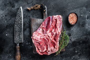 Raw Boneless Leg of Lamb meat on wooden cutting board. Black background. Top view