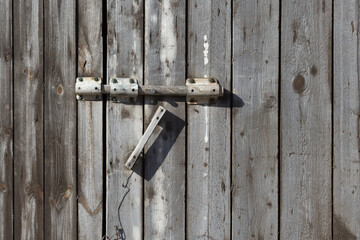 Wooden gate with a lock. Old bolt.