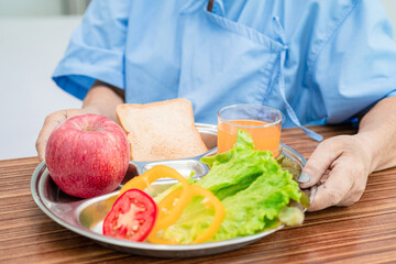 Asian senior or elderly old lady woman patient eating breakfast vegetable healthy food with hope and happy while sitting and hungry on bed in hospital.