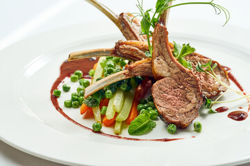 Appetizing grilled rack of lamb with vegetables and berry sauce in a white plate. Grey on white background.