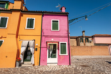 Fototapeta na wymiar Old small beautiful multi colored houses (bright colors) in Burano island in a sunny spring day. Venetian lagoon, Venice, UNESCO world heritage site, Veneto, Italy, southern Europe.