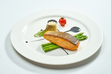 Grilled salmon steak with asparagus and balsamic sauce in a white plate. Isolated on white background. View from above