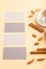 Composition of gray paper business cards, almonds, cinnamon and cup of coffee. mockup on orange background. side view, copy space.