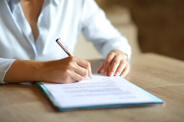 Close up of woman hands signing contract on table - obrazy, fototapety, plakaty