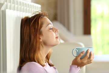 Woman relaxing on radiator holding coffee cup - obrazy, fototapety, plakaty