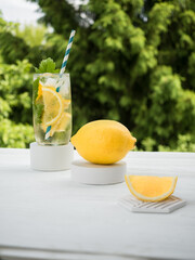 Still life concept: cold lemonade with ice, whole lemon and its slice on gray plaster coasters and...