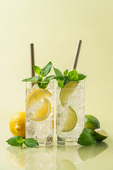 Refreshing lemonade with lime mint and ice. Pastel green background. Side view, copy space, minimal...