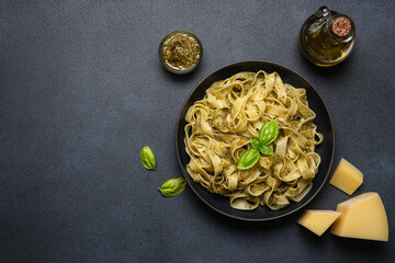 Pasta with pesto sauce, parmesan cheese and basil. Traditional Italian cuisine. Black background,...