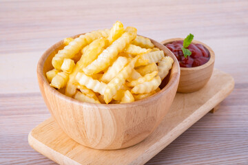 Tasty french fries and ketchup tomato sauce in wooden bowl on cutting board. Unhealthy junk food, High fat and calories. on wooden table background.
