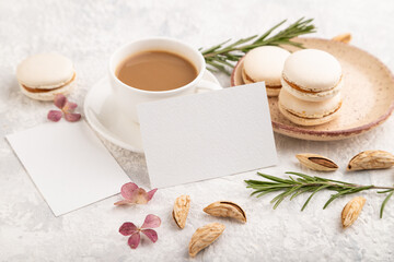 White business card mockup with cup of coffee, almonds and macaroons on gray concrete background. side view