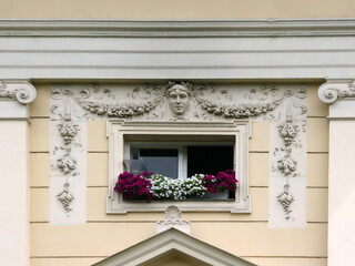 Window with ornaments above it and flowers in the flowerpot on the window sill