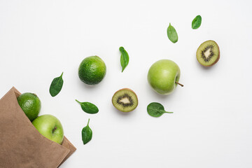 Green fruits and vegetables on white background. Kiwi, lime, apple, spinach. Green marketing concept