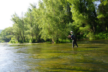 fly fisherman fishing in a small wild river