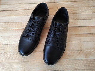 Black leather sports shoes on wooden background