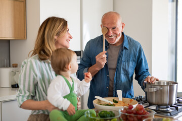Senior couple with granddaughter indoors at home, cooking.