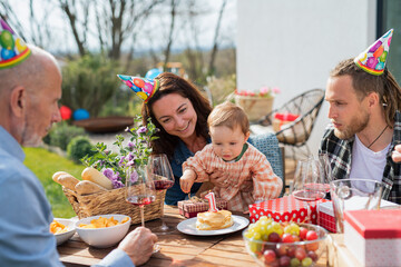 Happy multigeneration family outdoors in garden at home, birthday celebration party.