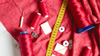 Creative sewing background, top view. Collection of various sewing tools , pattern, red fabric,...