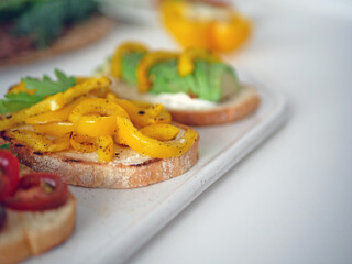 Vegan bruschetta. Delicious bruschetta with tomatoes, yellow peppers and avocado on a white plate. Appetizing Vegetable Snack Cheese Sandwiches