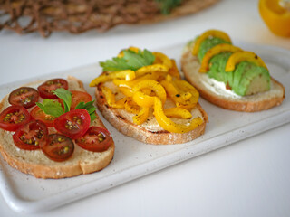 Vegan bruschetta. Delicious bruschetta with tomatoes, yellow peppers and avocado on a white plate. Appetizing Vegetable Snack Cheese Sandwiches