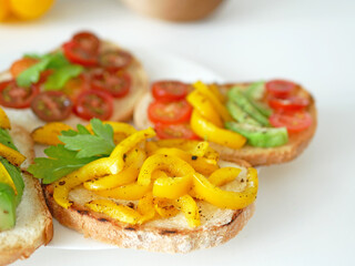 Vegan bruschetta. Delicious bruschetta with tomatoes, yellow peppers and avocado on a white plate. Appetizing Vegetable Snack Cheese Sandwiches