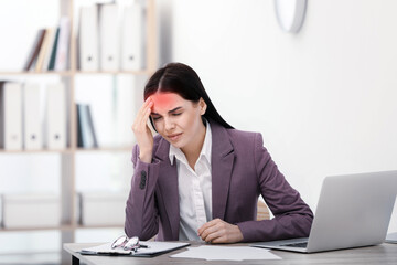 Woman suffering from migraine at workplace in office