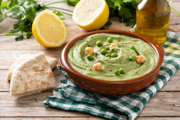 Green pea hummus and pita bread on wooden table
